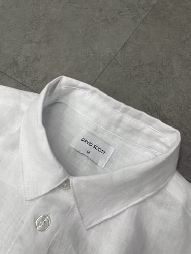 Customer's close-up of the white linen shirt's collar and tag, showing the fabric detail.
