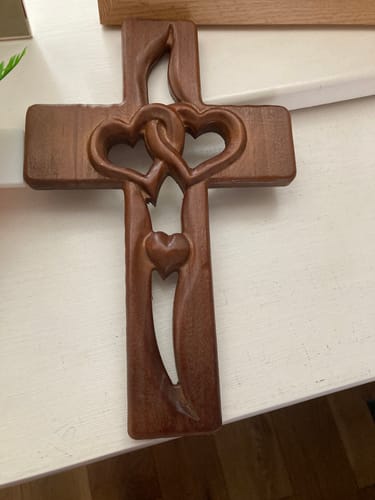 Customer's dark walnut Handcrafted Two Heart Cross with its carved design, resting on a white surface.