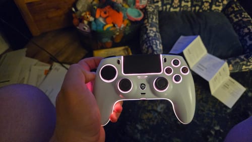 Customer holding the white wireless game controller, which is glowing with pink RGB lights.