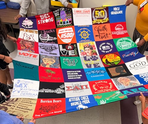 Customer's large, colorful Project Repat T-Shirt Quilt held up by several people.