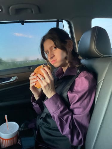 Customer wearing their BIRTHSTONE RING while sitting in a car and eating.