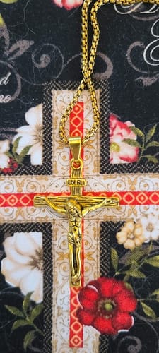 Customer's detailed, gold-colored Crucifix Pendant Charm Necklace on a patterned background.