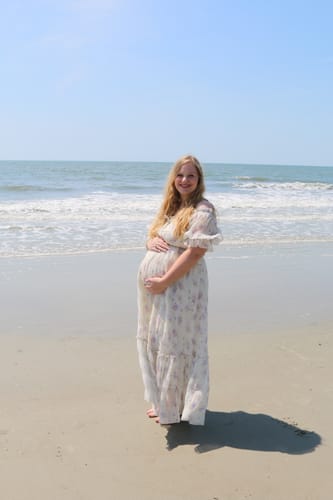 Pregnant reviewer on a beach wearing the floral Crinkled Chiffon Dress.