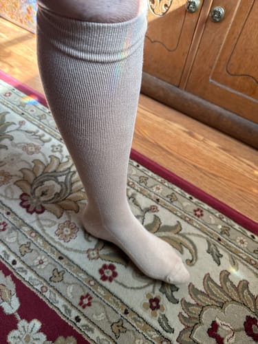 Customer wearing a light-colored, ribbed Eucalyptus Lyocell Compression Sock on their leg and foot.