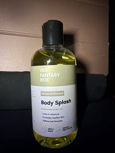 A customer's bottle of Santal Driftwood Body Splash, showing the yellow oil in a clear bottle with a black cap.