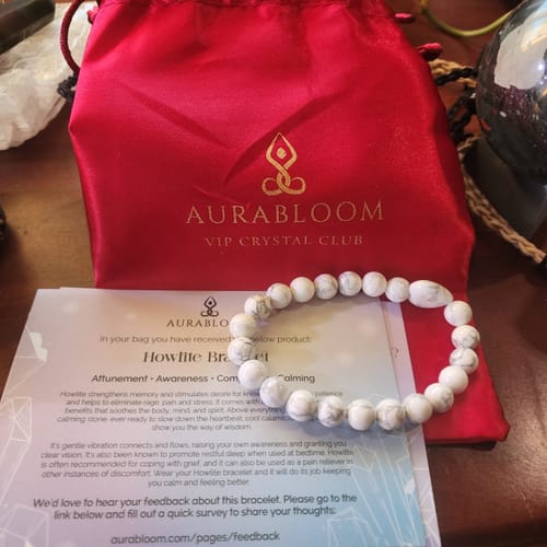 Reviewer's white howlite beaded bracelet from the VIP Crystal Club, shown with its red pouch and information card.