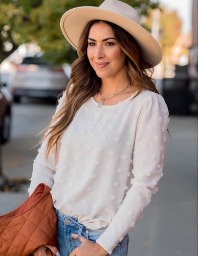 Reviewer wearing the white Textured Dot Long Sleeve Blouse outdoors, styled with jeans and a hat.
