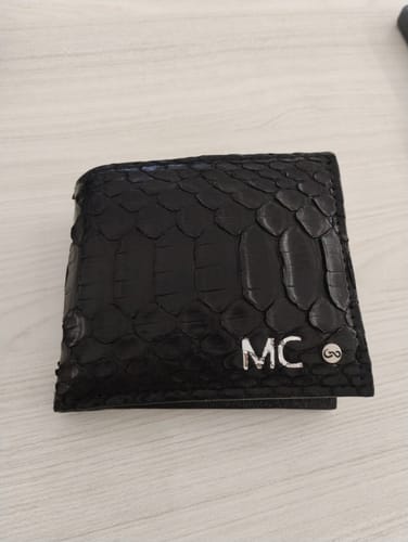 Un cliente muestra la Cartera 'The Grid' Python Black, personalizada con las iniciales 'MC' en plateado.