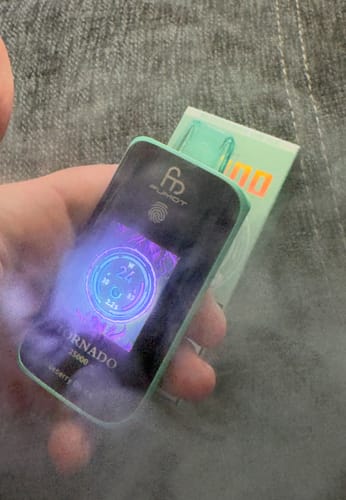 Kunde hält den mintgrünen RANDM TORNADO 25000 mit leuchtendem Display in der Hand, umgeben von Dampf.