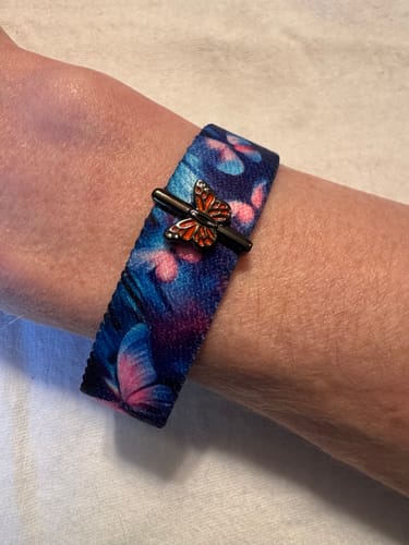Close-up of a reviewer's wrist wearing the blue and pink Change Is Beautiful Bracelet with an orange butterfly charm.