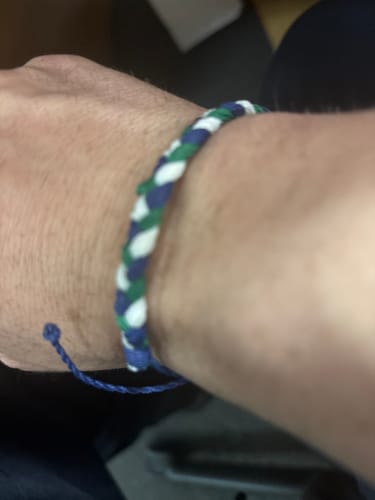 Close-up of a customer wearing the woven DAVID Bracelet, showing its blue, green, and white colors.
