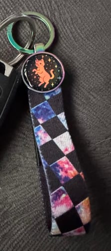 Reviewer's Forever Cool Bracelet with a cosmic checkered pattern, used as a keychain with an added caticorn charm.