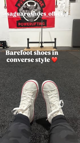 Customer's first-person view of their white Roam I - Barefoot Shoes while sitting on a gym floor.