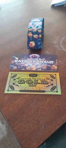 Customer's Bath-tronaut Bracelet on a table with its collector card and a special gold card.