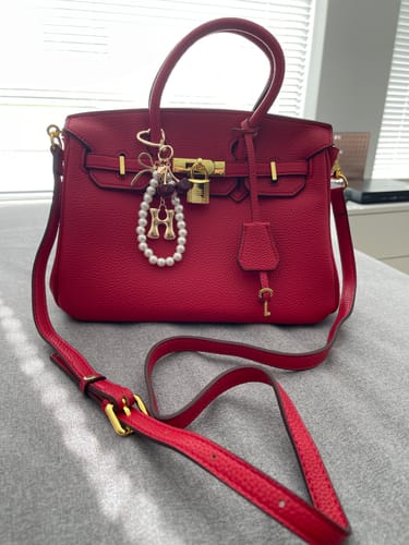 Reviewer's red LALUVA Warkin Bag shown in pebbled leather with its gold hardware and strap.