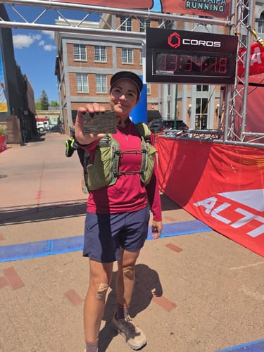 Customer celebrating at a race finish line after using PlayOn Pain Relief Spray during the event.