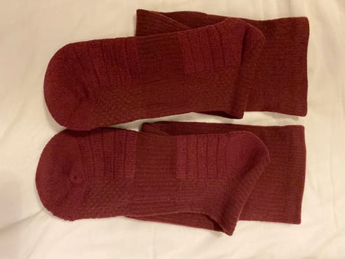 Kundens par mörkröda Diasocks stödstrumpor som ligger på en vit yta.