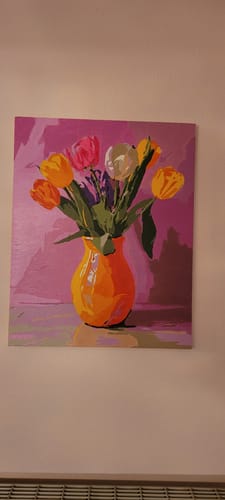 Ein Kunde zeigt das fertige Gemälde 'Malen nach Zahlen - Tulpenstrahlen', das einen bunten Tulpenstrauß in einer Vase darstellt.