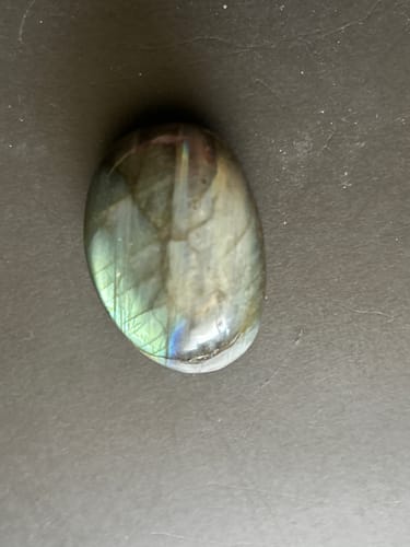 Reviewer's polished labradorite crystal showing iridescent flashes of green and blue.