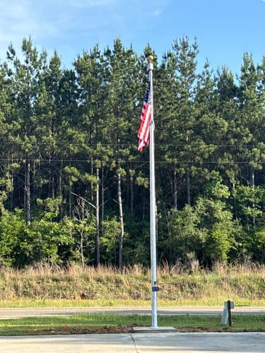 Customer's gold ball ornament shown on a tall flagpole installed outside a fire station.