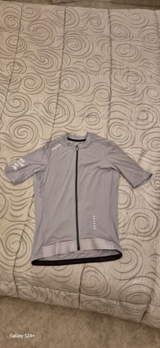 Customer's gray VIVIDNESS JERSEY laid flat on a bedspread, showing the full-zip front and short sleeves.