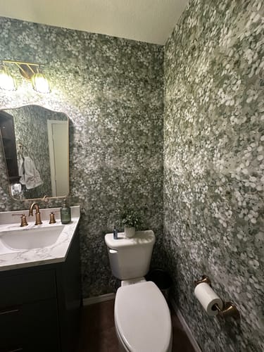 Customer's bathroom with the green and white Ridge Wallpaper applied to the walls around a vanity and toilet.