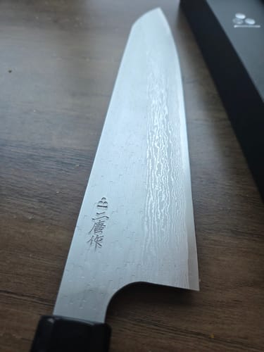 Close-up of the customer's Nigara Hamono Gyuto blade, showing the Damascus pattern and maker's mark.