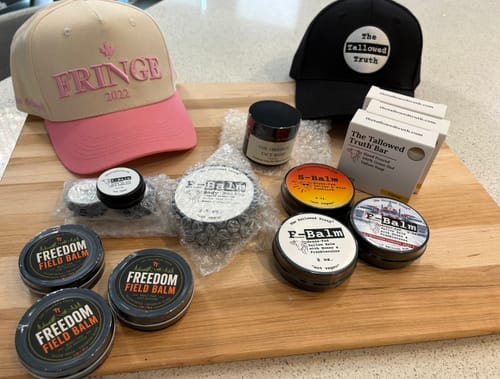 Customer's collection of products, including F-Balm lip balm tins and hats, arranged neatly on a wooden board.