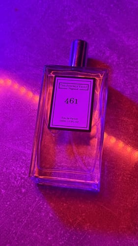 Reviewer's 461 perfume bottle on a textured surface under dramatic purple light.