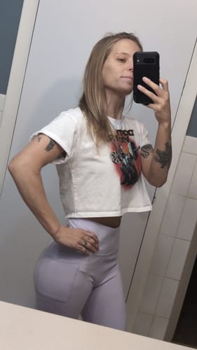 Reviewer taking a mirror selfie showing the relaxed fit of the white Depth Loose Crop Top.