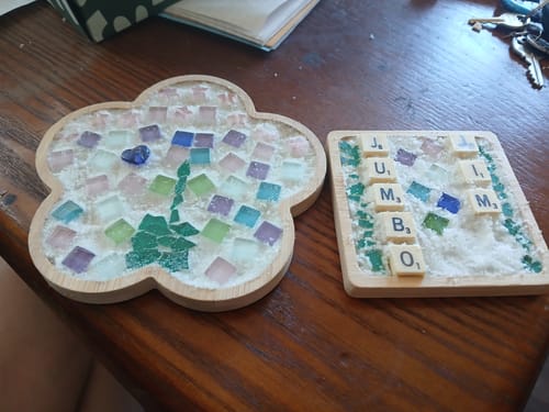 Customer's two finished mosaic coasters from the craft DIY subscription box, one flower-shaped and one square.