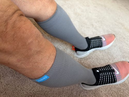 Reviewer sitting down while wearing the grey Eucalyptus Lyocell Compression Socks and sneakers.