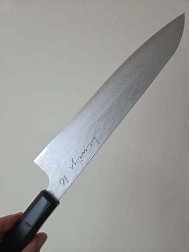 Customer holding the Nigara Hamono Gyuto, showing the full blade with a custom script engraving.