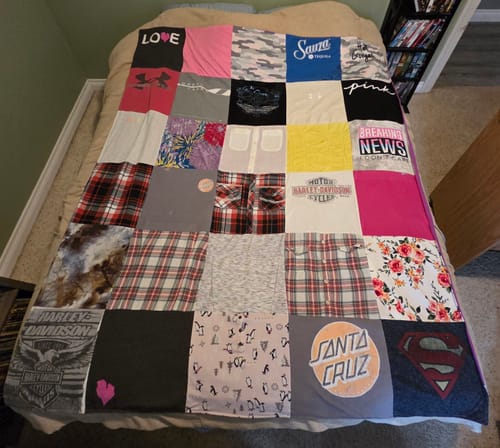 Customer's custom Project Repat T-Shirt Quilt spread on a bed, made with a colorful grid of t-shirts and flannel.