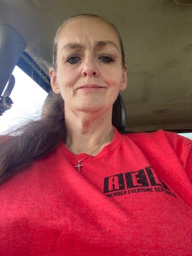 Reviewer wearing the red R.E.D. Friday Tee while sitting in a car.