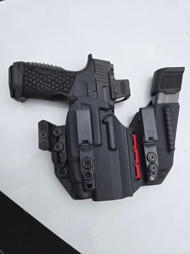 A customer's black AXIS ELITE holster with red shock cord, holding a firearm and spare magazine.