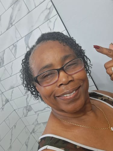 Reviewer smiling and pointing to her defined curly hair after using the SET Gel-To-Foam Styling Mousse.
