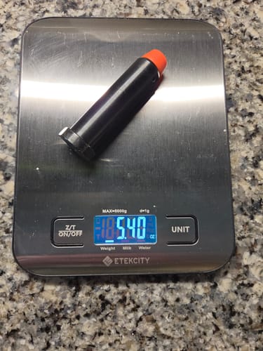 Reviewer's black AR-15 H3 Heavy Buffer on a digital scale showing a weight of 5.40 oz.