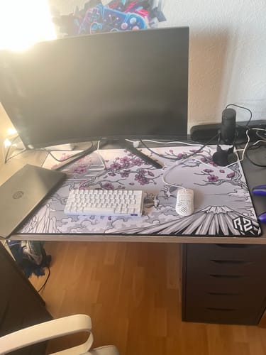Rezensent zeigt das RZ Mousepad Sakura White auf einem Schreibtisch als Teil eines Gaming-Setups.