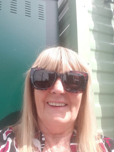 Customer smiling while wearing the oversized floral Polarized Fit Over Sunglasses outdoors.