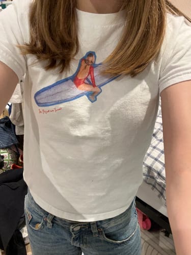 Reviewer wearing the white air dry baby tee with a colorful surf graphic.