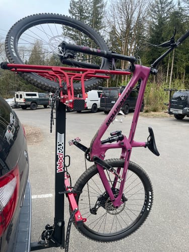 Customer's purple mountain bike with the Clear Frame Keeper installed, mounted on a car bike rack in a parking lot.