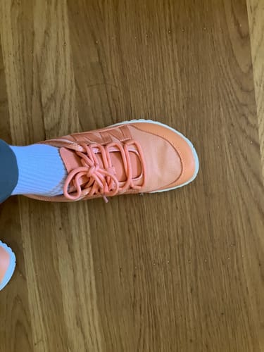Reviewer's top-down view of their orange Forestep Ⅰ Barefoot Shoe on a wood floor.