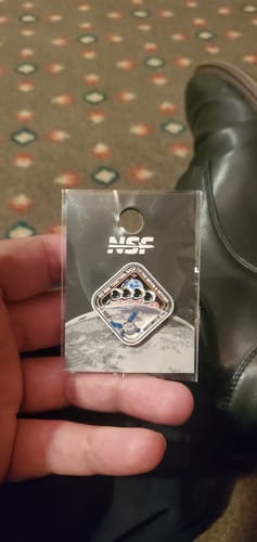 Customer holding the Artemis II - Collectors Pin in its original NSF branded packaging.