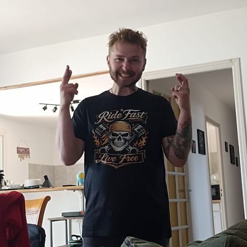 Un client souriant porte le t-shirt noir Pirate Ride Fast Live Free à l'intérieur.