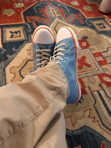 Customer wearing the blue Gulf High-Top Canvas Sneakers with feet crossed on a colorful rug.