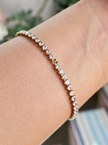 Customer wearing the delicate, gold-tone Tennis Bracelet on their wrist.