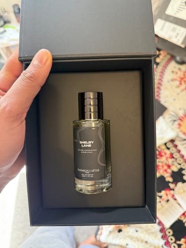 Customer holding a black box open, showing the bottle of Thomson Carter Eau de Parfum inside.