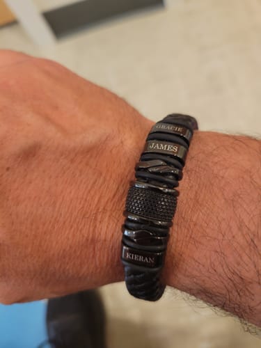 Customer wearing the black bracelet personalized with the engraved names Gracie, James, and Kieran.