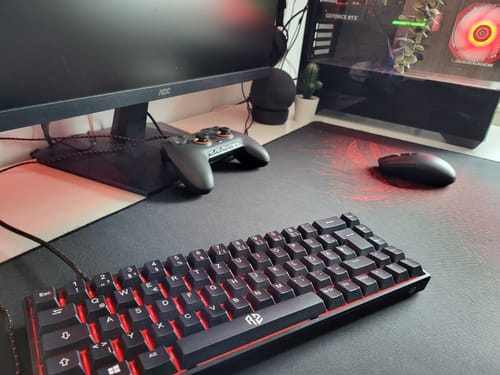 Rezensenten-Foto der schwarzen RZ 65 HE Gaming-Tastatur in einem Gaming-Setup mit roter Beleuchtung.